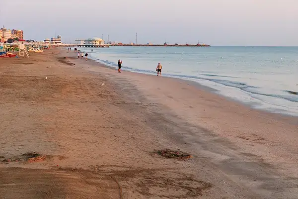 Spiaggia prospiciente il mare con lettini e persone a passeggio