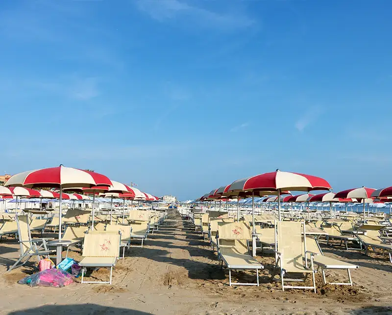 File di ombrelloni a spicchi bianchi e rossi sulla spiaggia